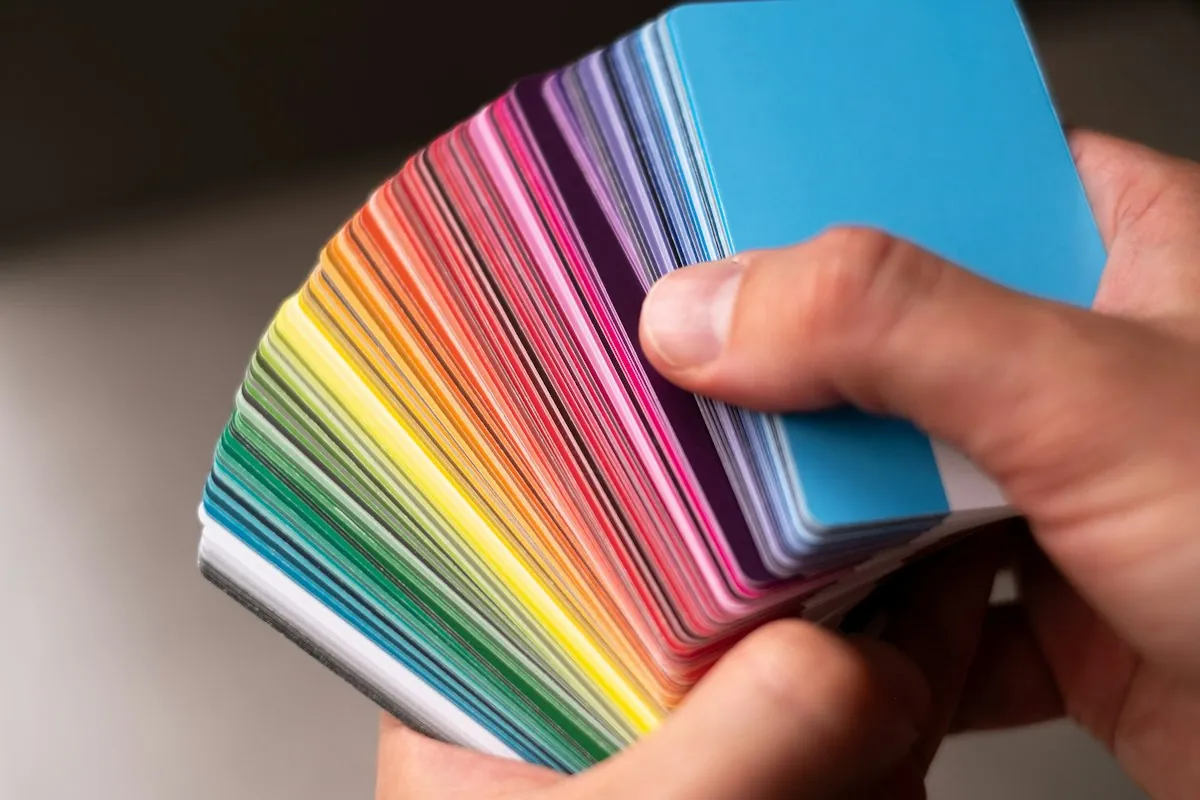 Color consultant holding a fanned paint color swatch deck to compare paint colors